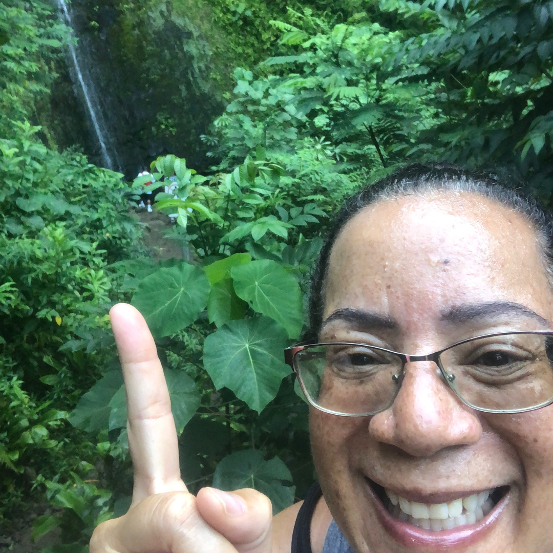 Author, Jill Hodge, pointing to Manoa Falls in Oahu, Hawaii.