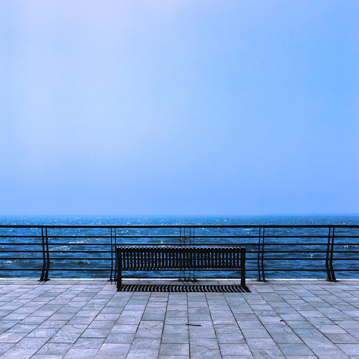 Photo of a bench in front of a cobalt blue ocean