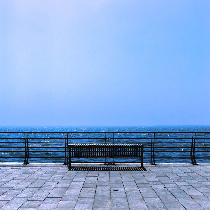 Photo of a bench in front of a cobalt blue ocean